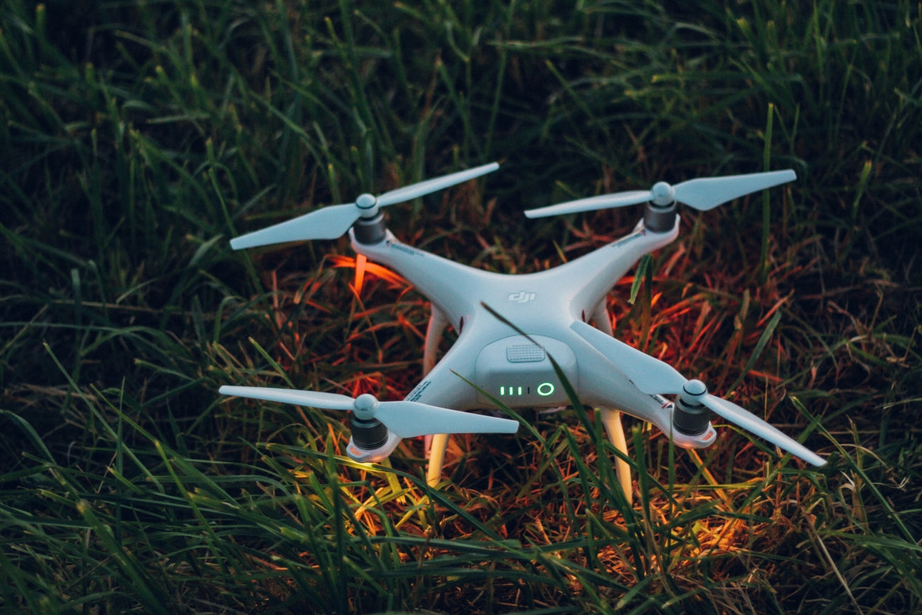 A DJI Phantom drone with glowing LED lights sitting on grass at dusk, prepared for takeoff – Loft Shelf electronics gadgets.